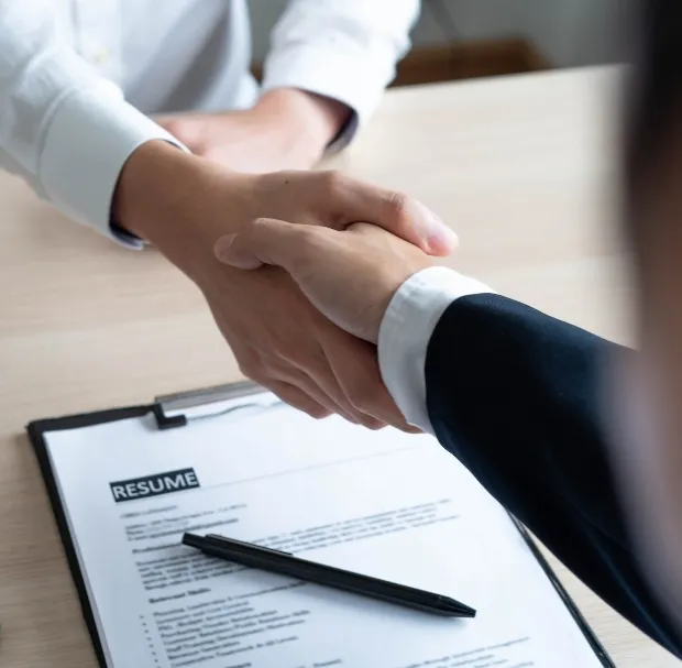 A picture of handshake confirming the hiring of an individual background showing resume One of the best healthcare recruitment agencies in toronto Your Talent Consultancy